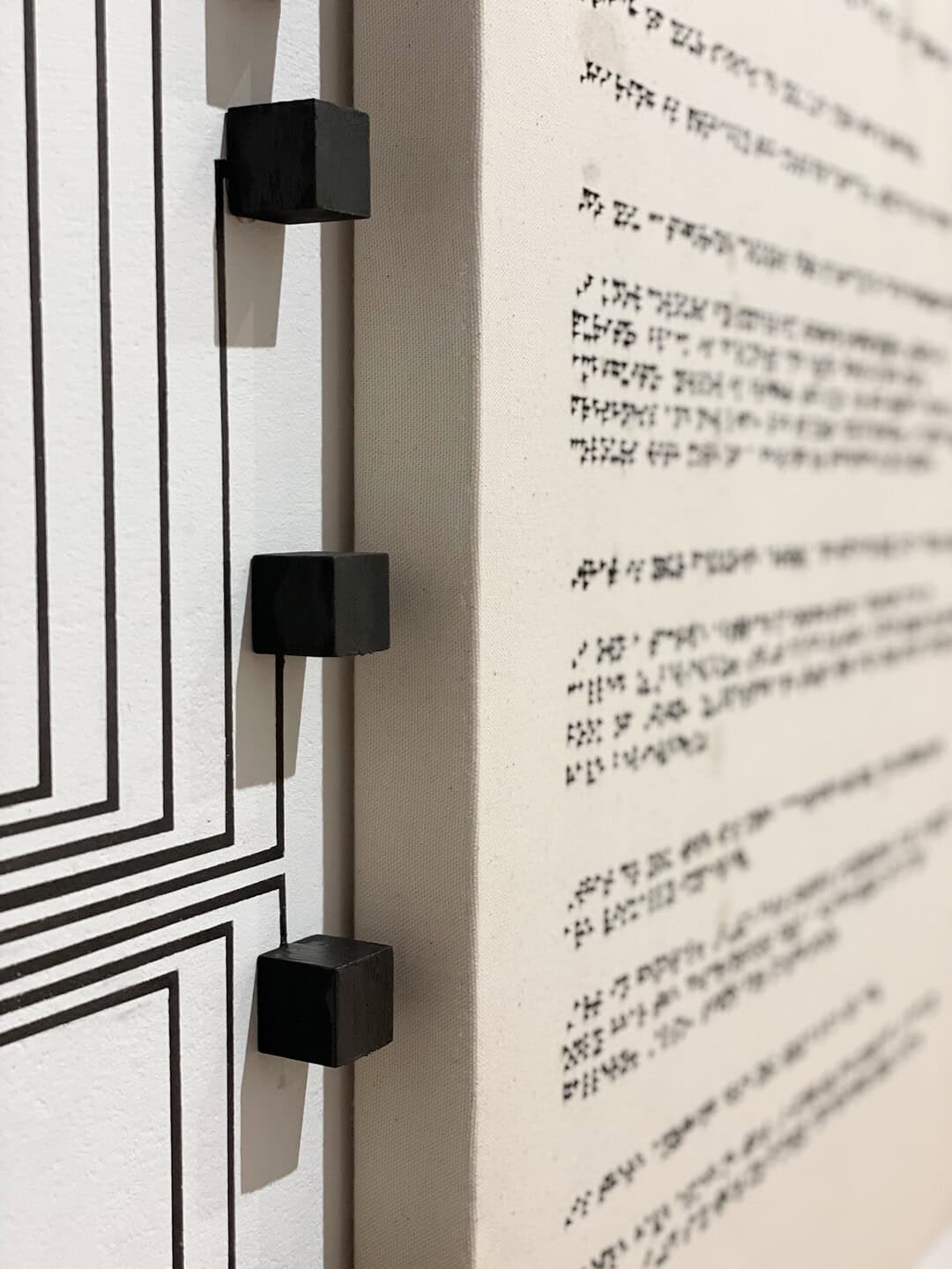 Close-up detail of small black square nodes and connecting lines beside a panel with braille text