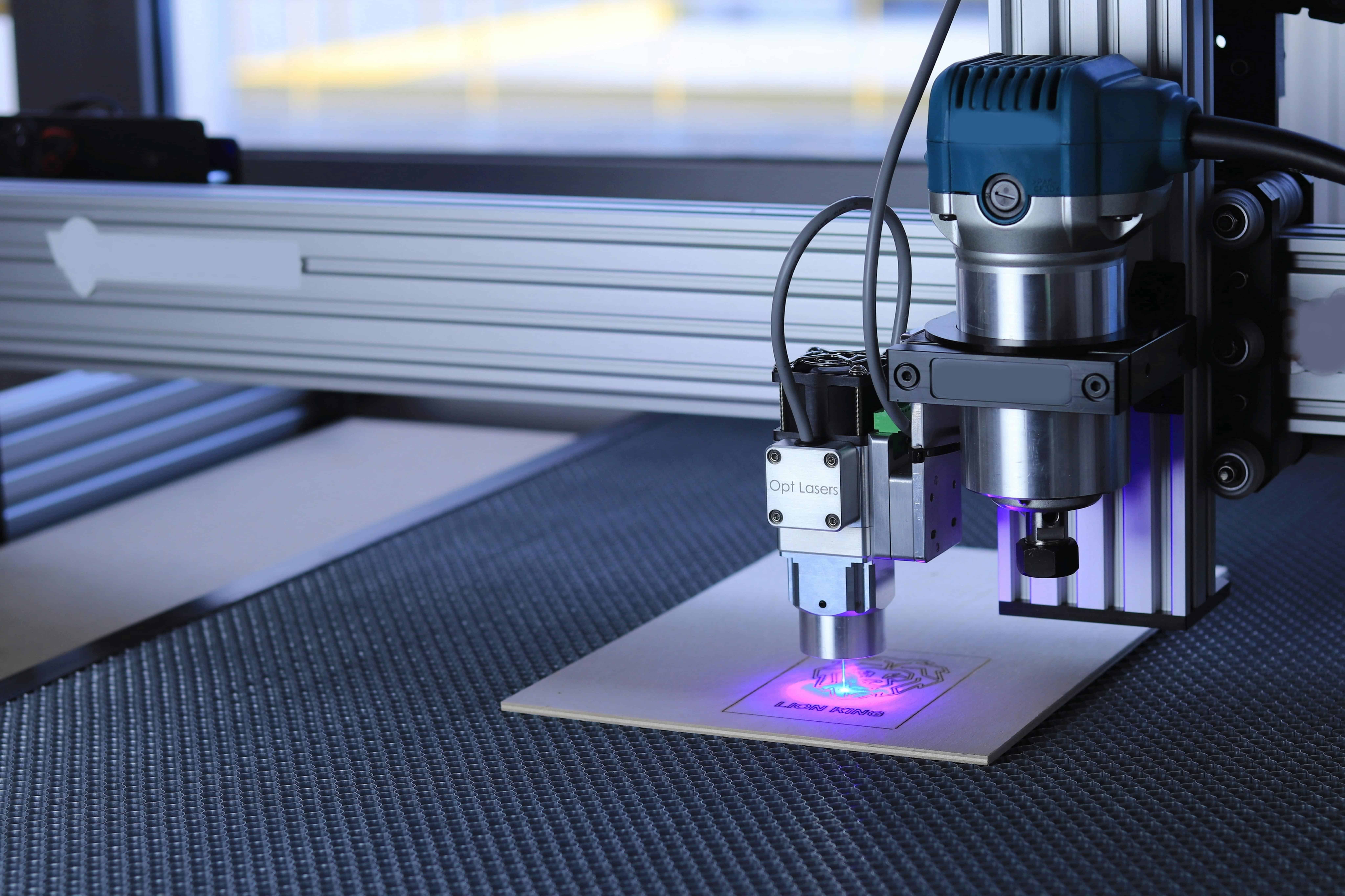 A laser cutter etching a design, emitting blue-violet light inside its enclosure.