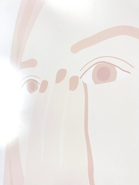 Close-up of a faint, minimalist face drawing with soft pink lines and simplified eyes and features