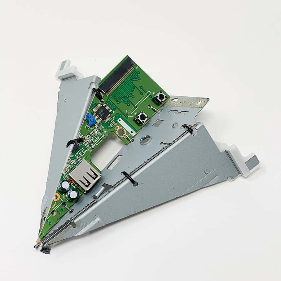 Triangular assembly made from gray metal brackets and a green circuit board with buttons, ports, and small electronic components, photographed on a white background.