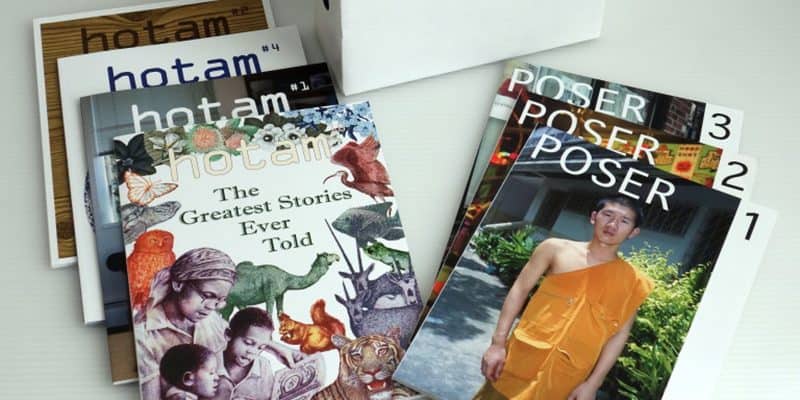 Several magazines are displayed on a table, including issues titled hotam with illustrated and text covers, and three issues of POSER, one featuring a person in an orange Buddhist monk robe.