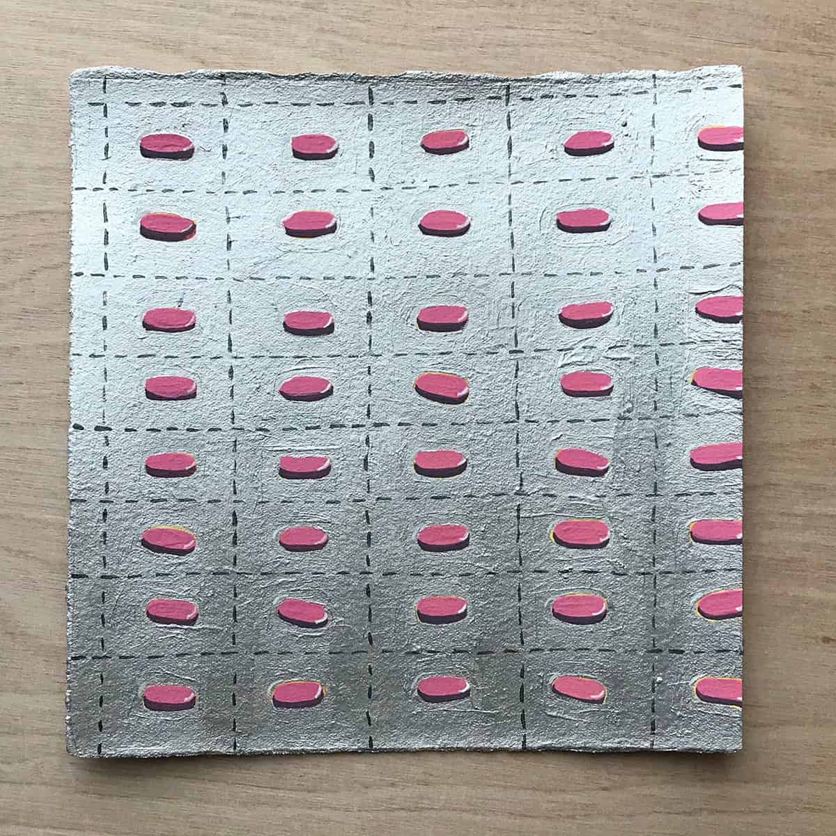 Small square artwork featuring a grid of pink capsule shapes on a silver metallic surface, evoking themes of medication and repetition.