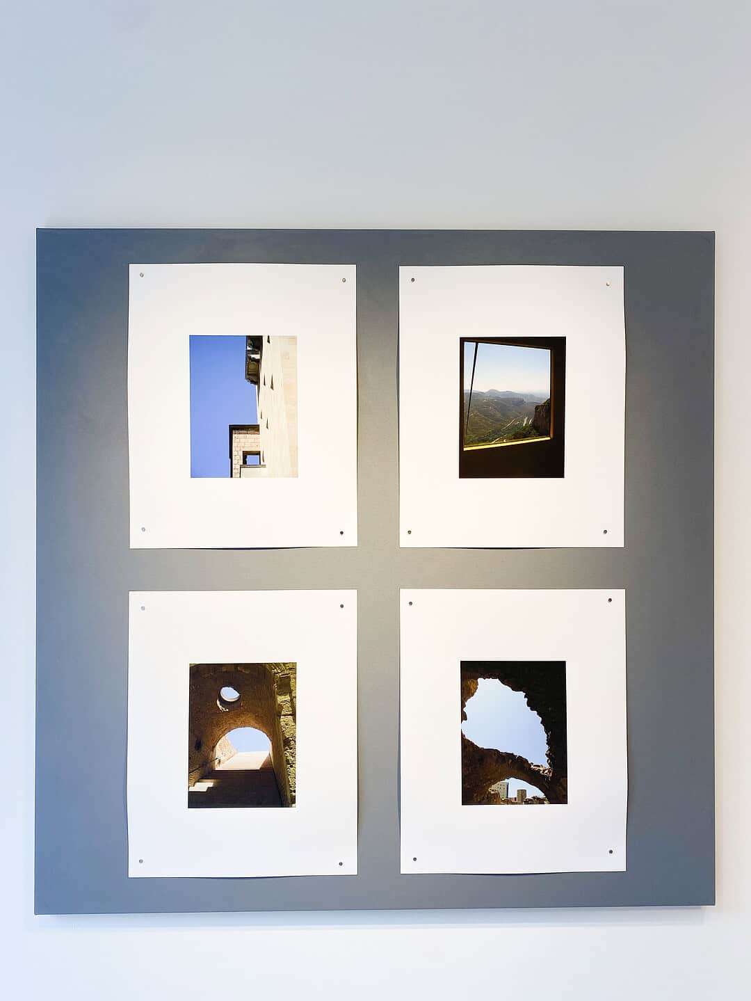 Four colour photographs of architectural views, each framed within white mats on a grey panel.