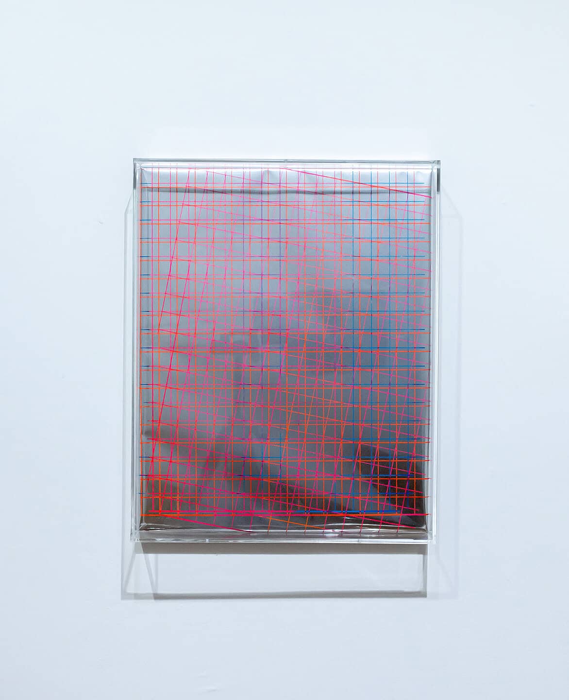 Square abstract artwork in a clear case featuring intersecting red grid lines over a muted grey-blue background