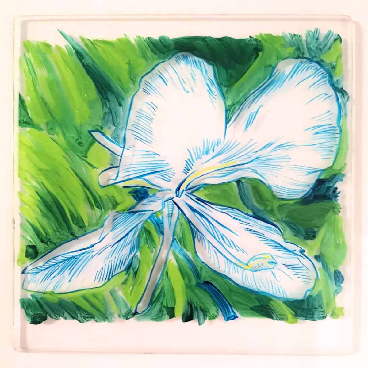A monotype print on a square glass tile featuring a blue and white flower with detailed line-work, set against a vibrant green background. The stylized flower has four large white petals.