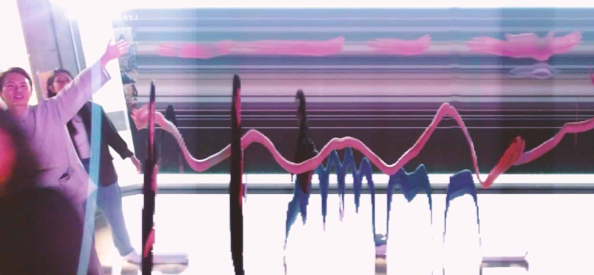 A slit-scan projection stretching figures into streaks of pink, blue and black across a wall.